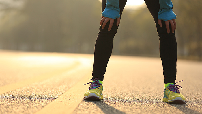 Runner Holding Knees And Taking A Break On Road