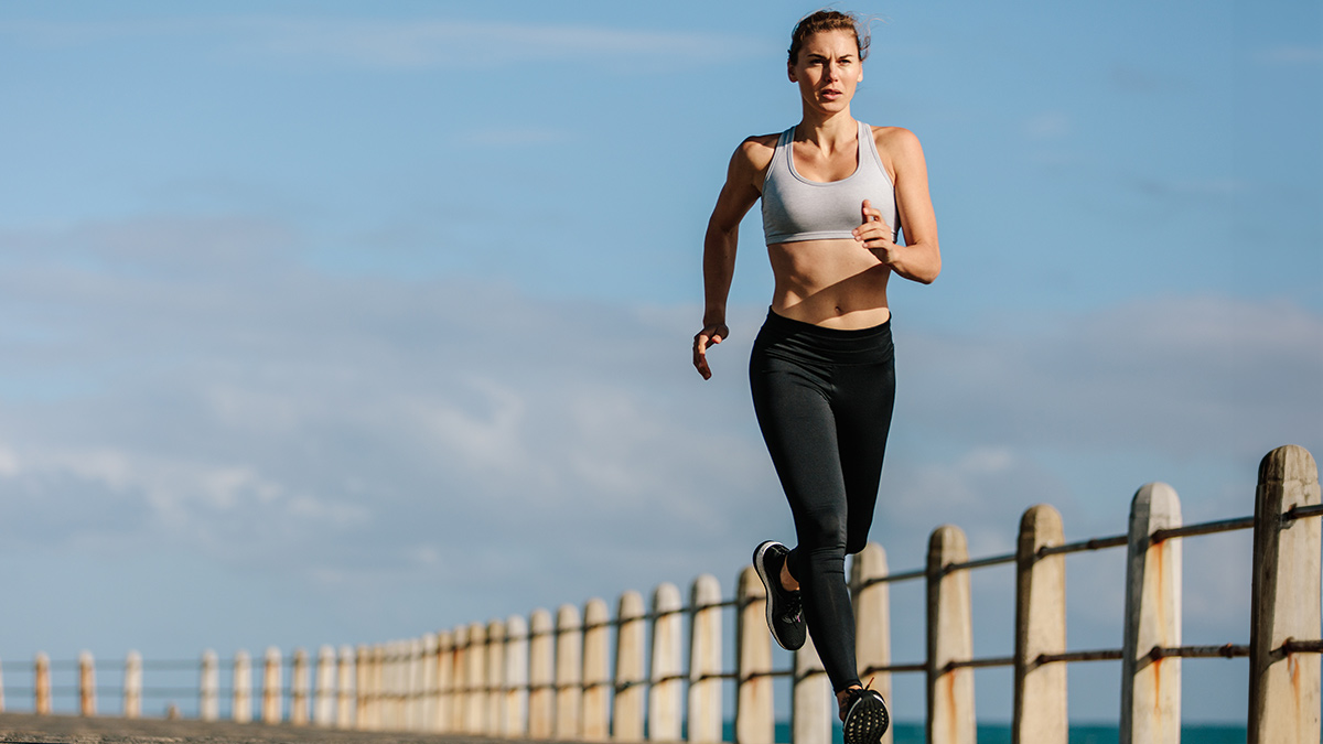 Efficiency Factor In Running Female Runner Athlete Running Along Concrete Road In Sports Bra And Leggings.