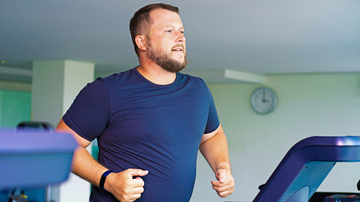The Key To Sustainable Weight Loss Is Regular Activity Slightly Overweight Man Exercising On Treadmill In Order To Obtain Sustainable Weight Loss