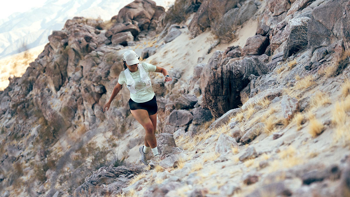 A Woman Trail Running On Rugged Desert Terrain