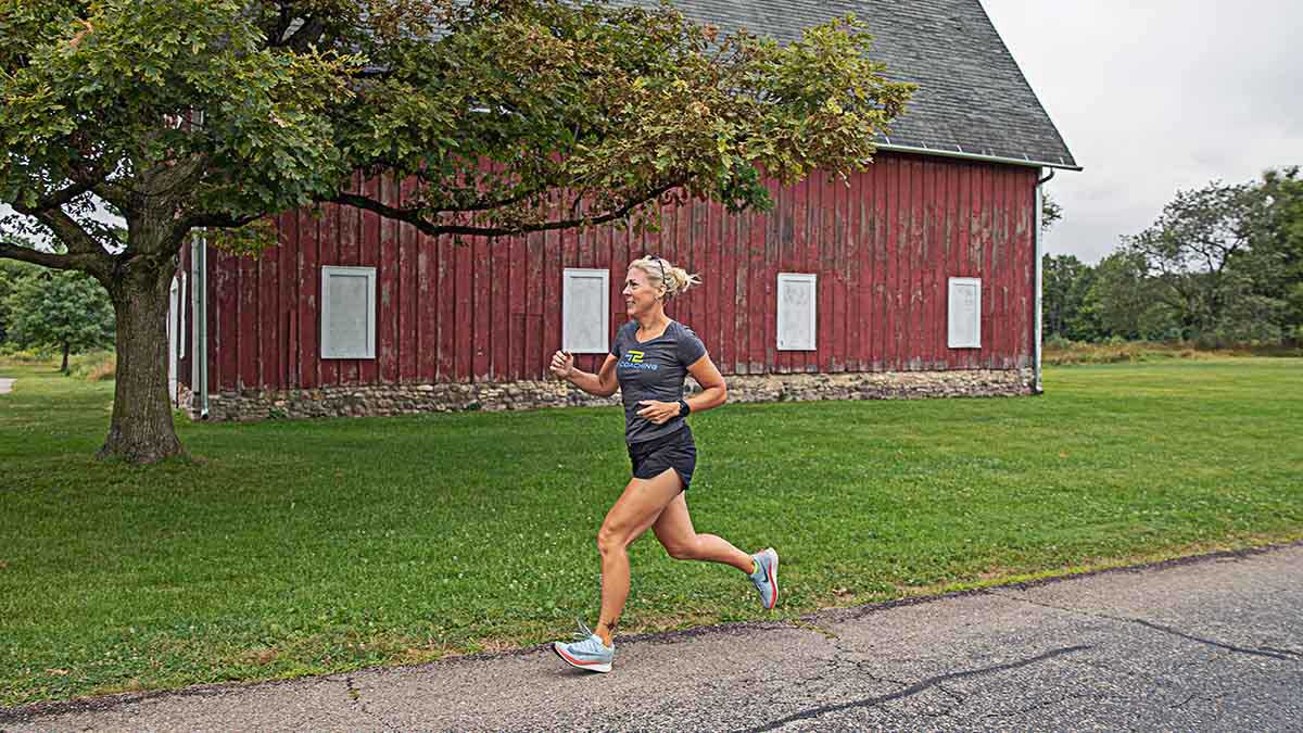 Coaching Perimenopause Menopause Athletes A Woman Running On The Road With An Old Barn In The Background