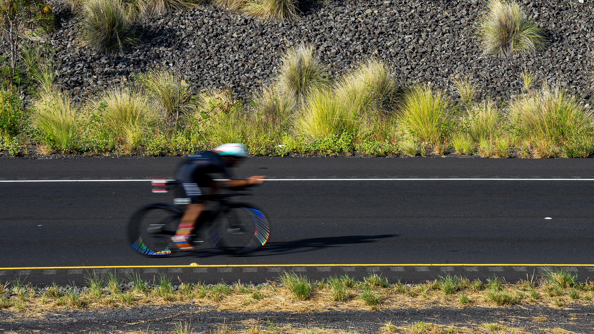 Ironman World Championships Hawai’i 2022 A Cyclist Is A Blur In A Slow Shutter Image Of A Highway Near Kona, Hi.