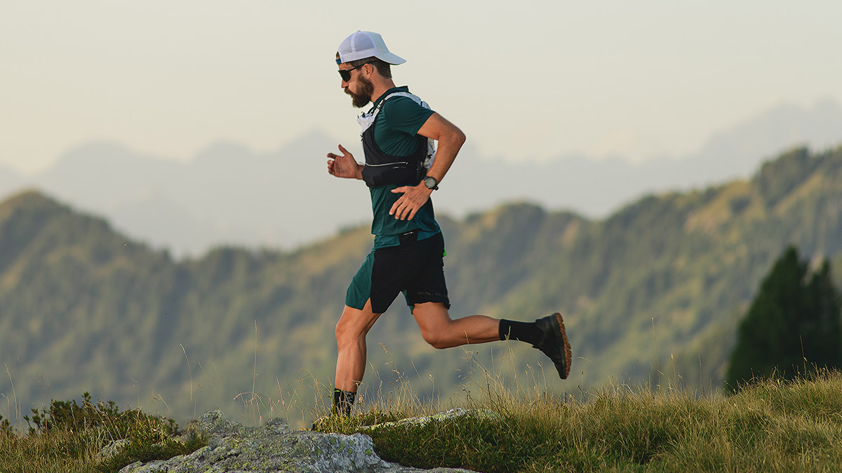 Trail Runner Male Athlete Running In The Mountains With Tshirt, Shorts, And Hat