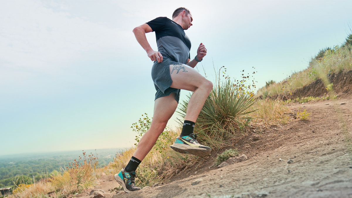 Running Power Basics A Man Running Up A Hill On A Trail In Shorts And A Shirt.