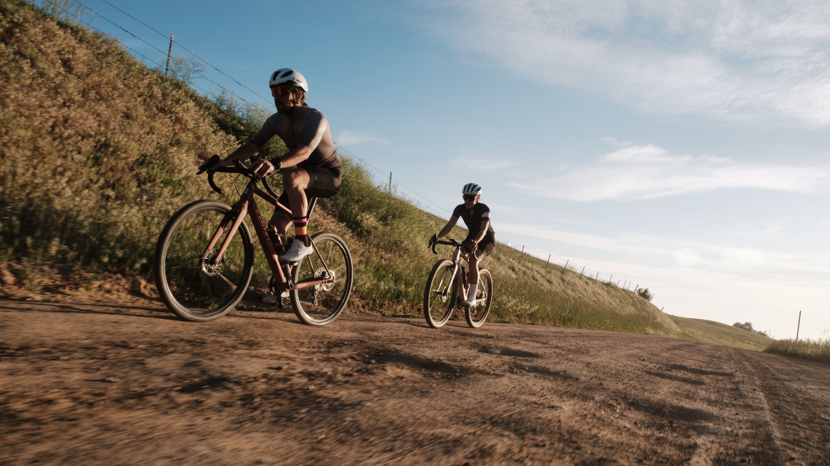 Two Gravel Cyclists Climbing Uphill Outside