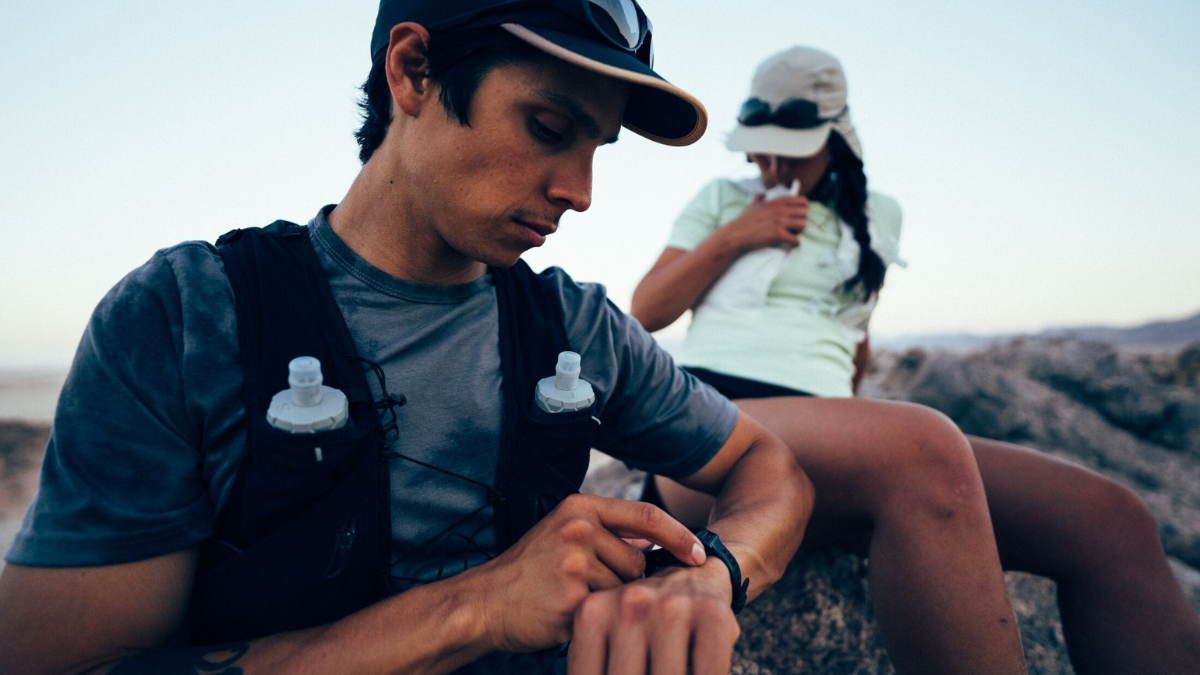 Trail Runner Looking At Watch On Top Of Mountain Checking Lactate Threshold